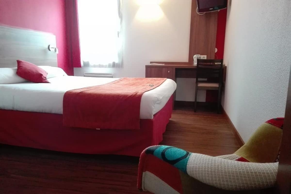 Een hotelkamer met een bed, een bureau en een stoel.