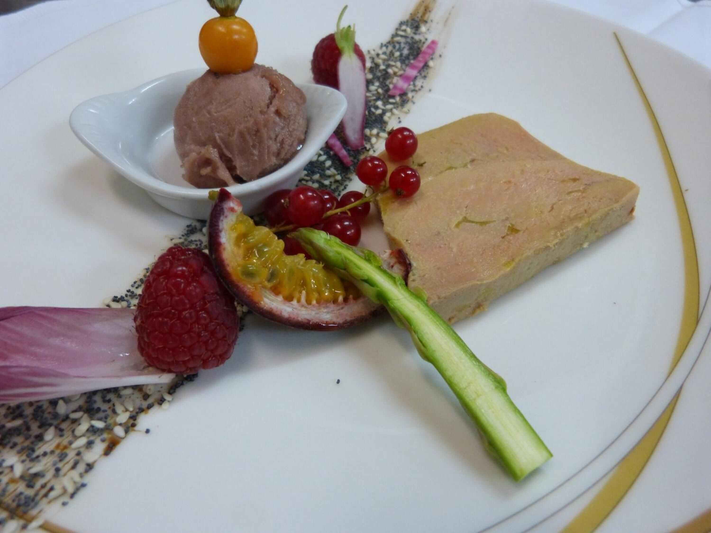 Une assiette contenant une tranche de viande, une boule de glace et divers fruits et légumes.