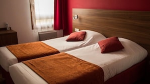 Een tweepersoonsbed met een houten hoofdbord, twee kussens en een bruine deken.