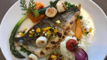 Ein Teller mit gegrilltem Fisch, Gemüse und Reis.