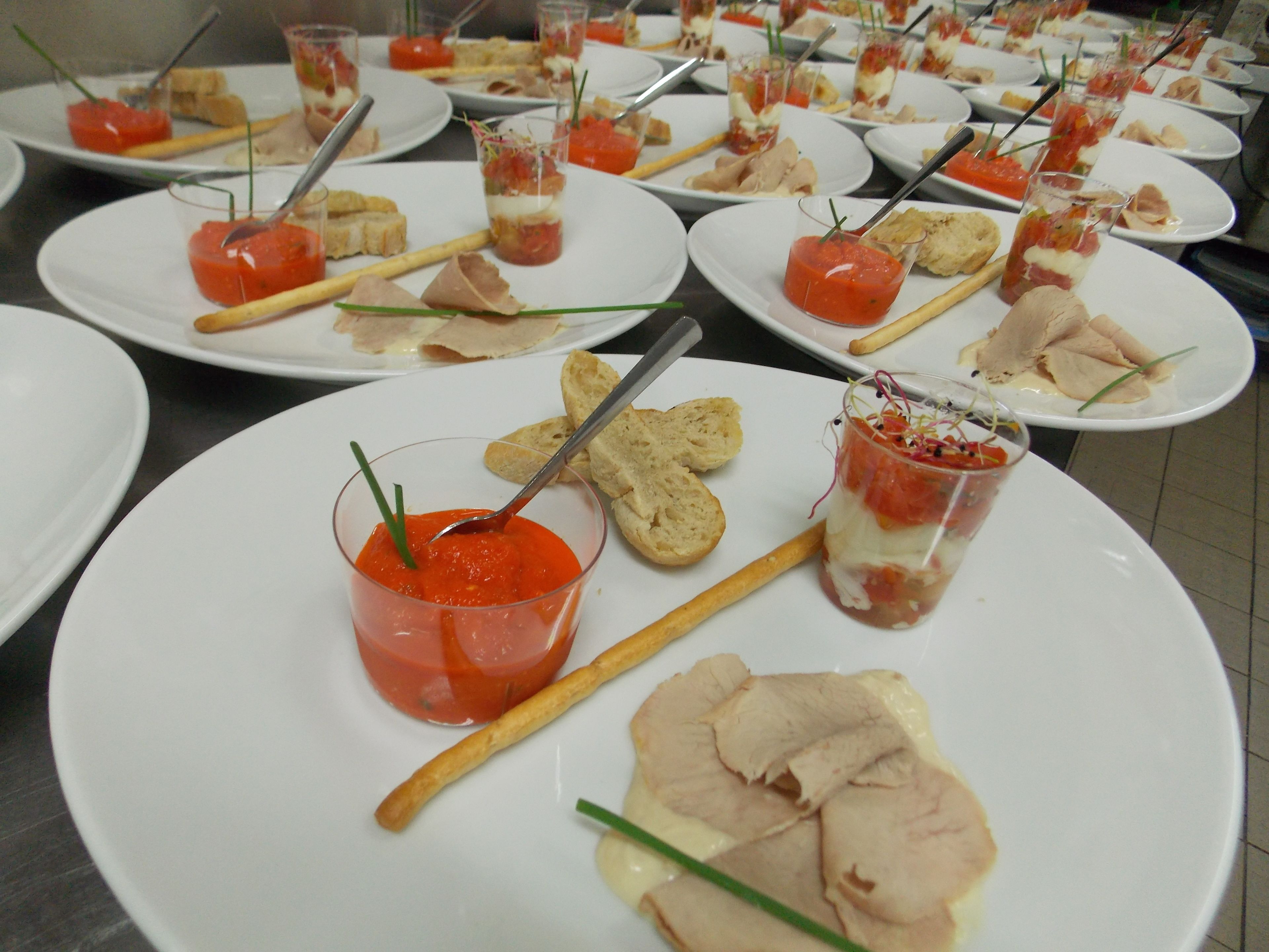 A buffet table with various food items, including small glass containers with red sauces and breadsticks.
