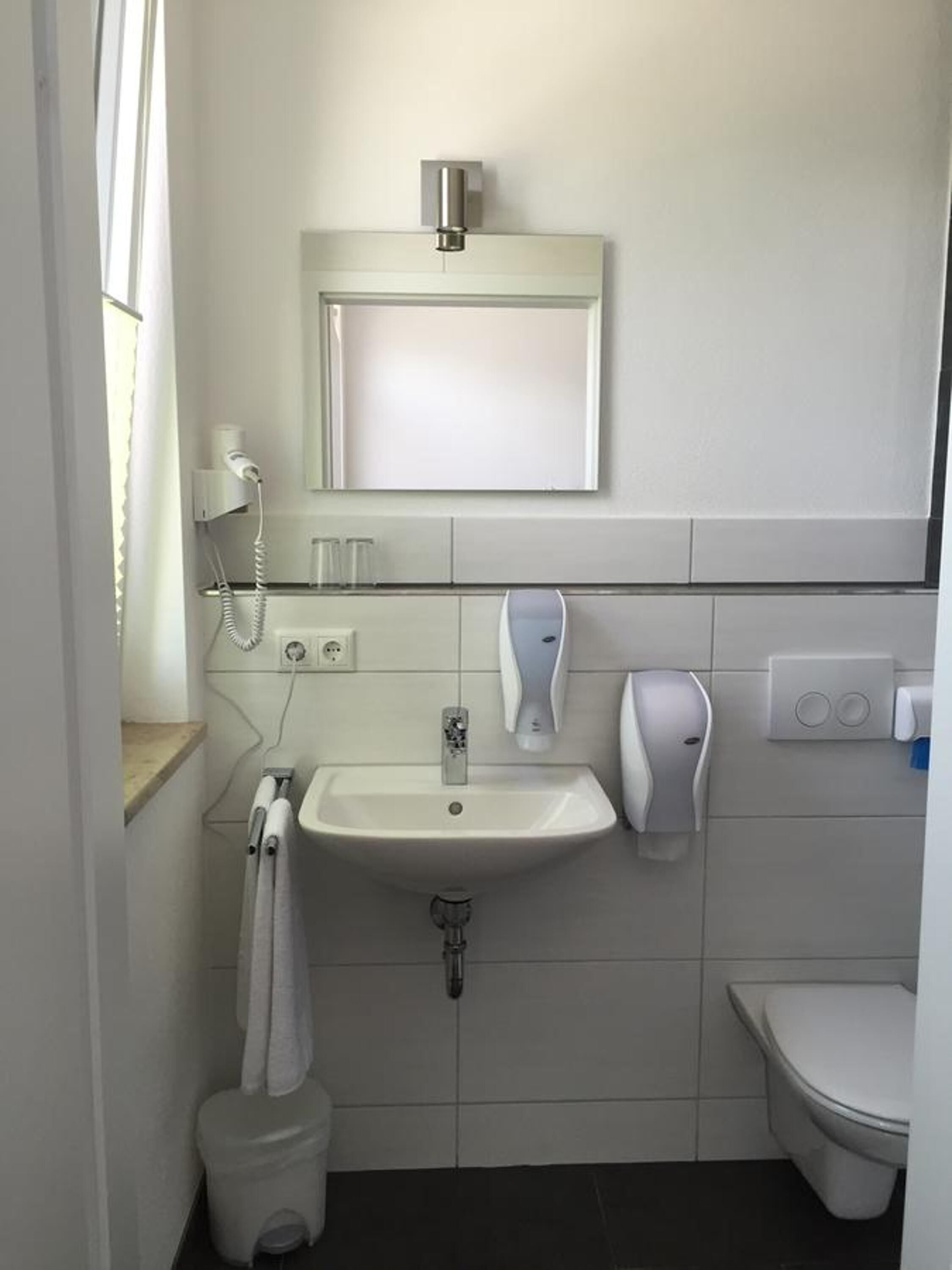 A compact bathroom with a white sink, a toilet, and a mirror above the sink.