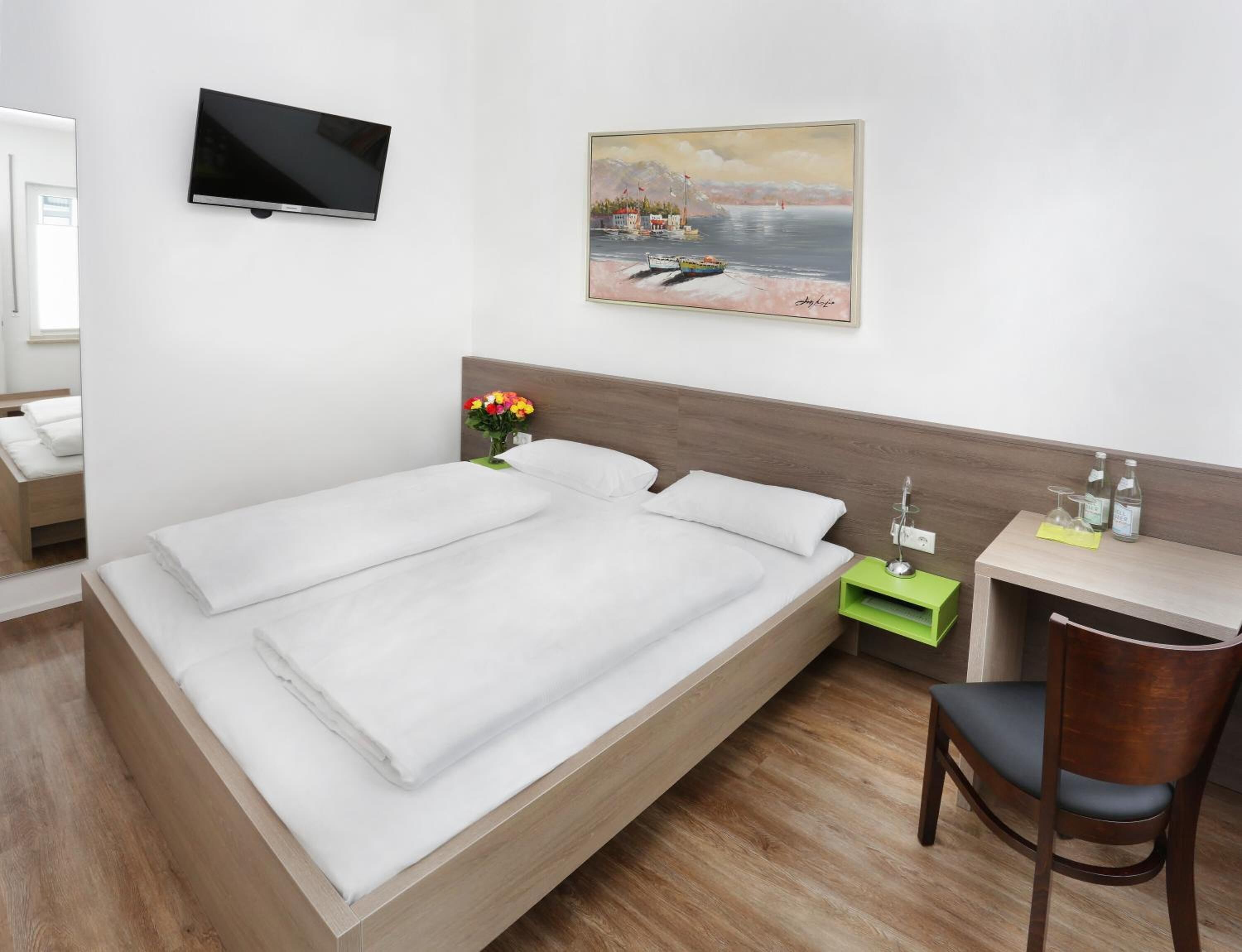 Una habitación de hotel moderna con una cama, un escritorio, una silla, un televisor y un cuadro en la pared.