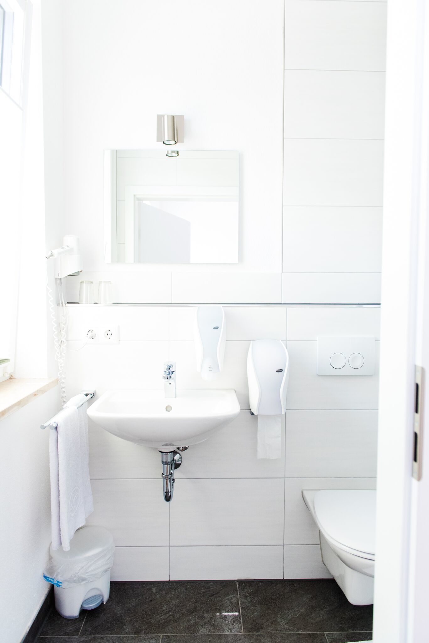 Une salle de bain moderne et compacte, avec un lavabo blanc, des toilettes et un miroir au-dessus du lavabo.