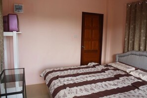 A bedroom with a bed, a door, a shelf with a purple object, and a patterned curtain. - Panna Kalong (Chiang Khong)