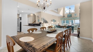 A spacious dining area with a wooden table, chairs, and a chandelier. - Portside S "beauty And The Beach" 3 Bedroom Townhouse by RedAwning (Pensacola Beach)