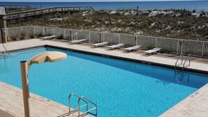 A swimming pool with a wooden deck, lounge chairs, and a view of the beach and ocean. - Portside S "beauty And The Beach" 3 Bedroom Townhouse by RedAwning (Pensacola Beach)