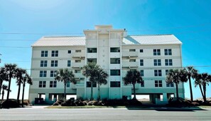 A multi-story hotel with a central atrium, balconies on each floor, and palm trees in the foreground.