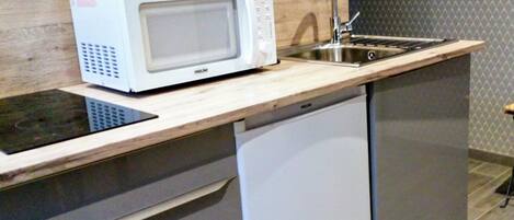 Una cocina compacta equipada con microondas, lavaplatos y fregadero.