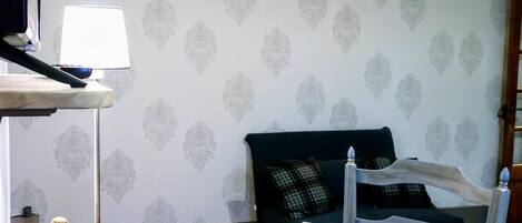 Una sala de estar acogedora con un sofá verde oscuro, un sillón blanco, una mesita de madera con un libro y una pequeña figurita verde.