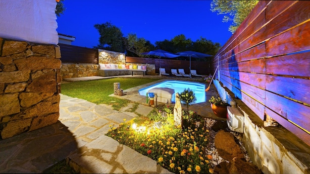 Ein Garten mit Schwimmbecken, Kiesweg und Blumenbeeten.