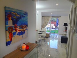 Un interior moderno con comedor, un cuadro de un barco y vistas al exterior.