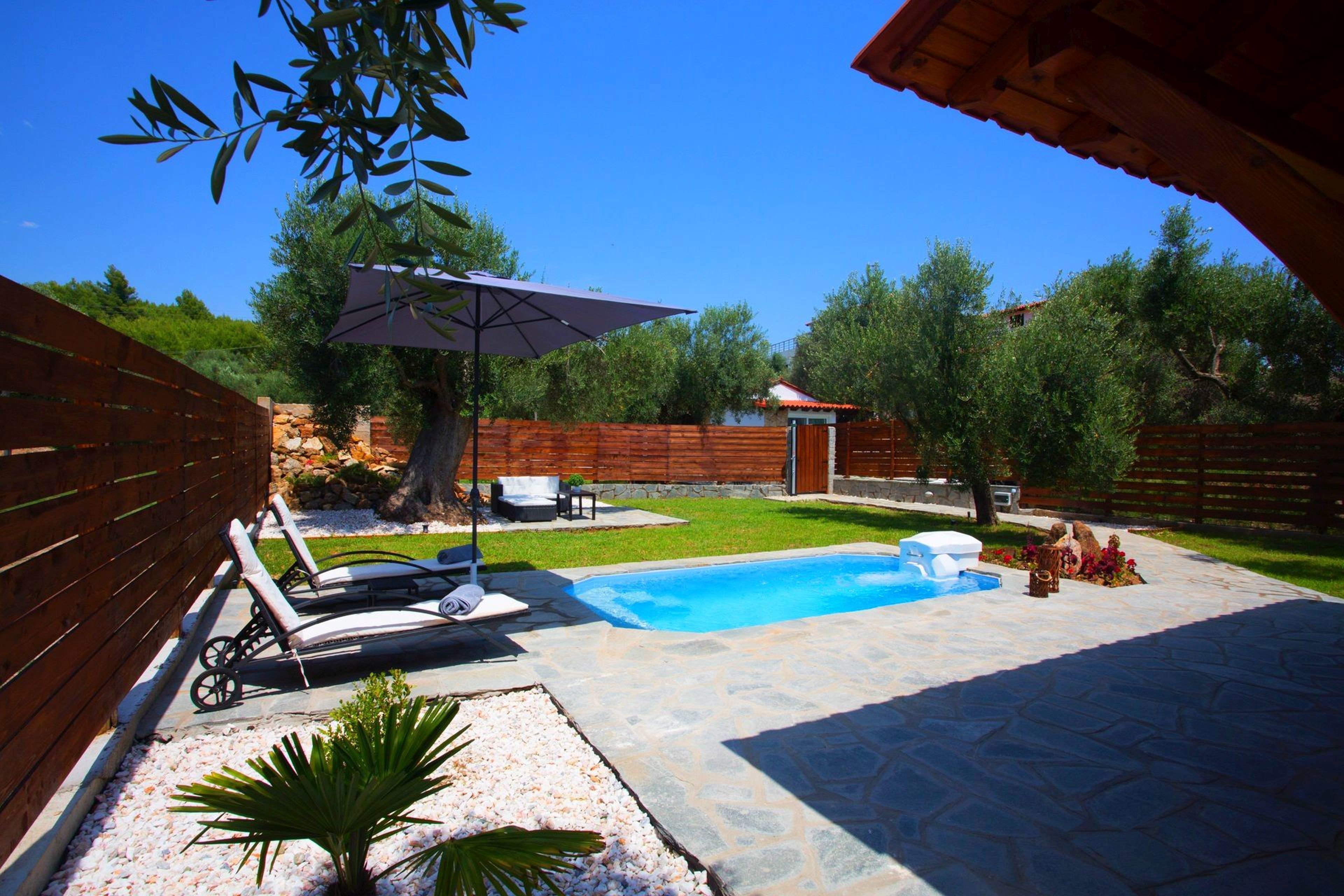 Ein Garten mit Swimmingpool, Liegestühlen und einem Holzzaun.