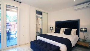 Ein modernes Schlafzimmer mit einem großen Bett, einer Glastür zu einem Außenbereich und einem Nachttisch mit Lampe.