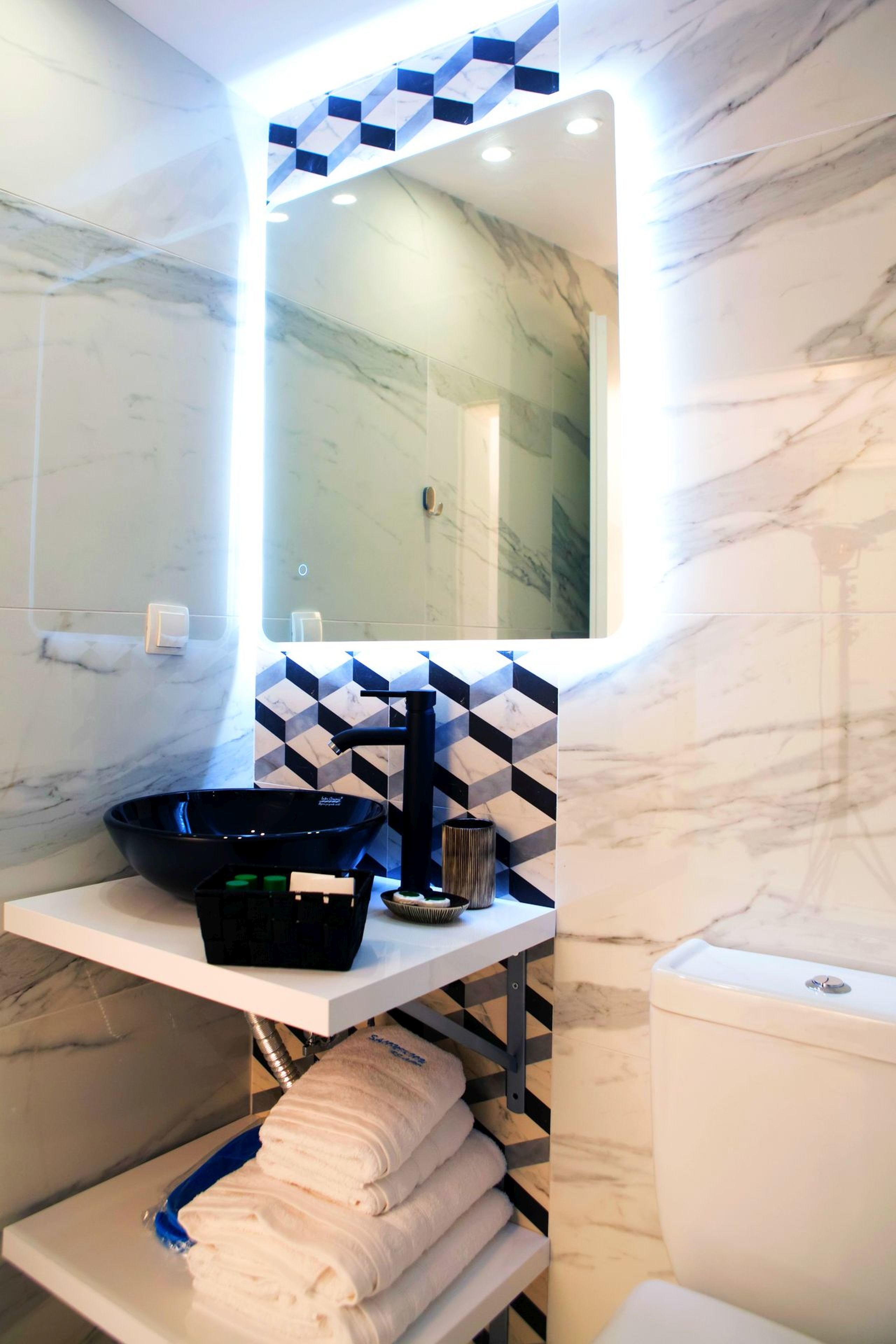 A modern bathroom with a black sink, a mirror, and a toilet.