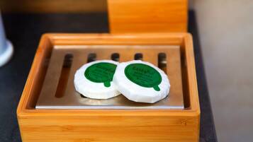 Two white bars of soap with green labels in a wooden box.