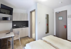 Quarto de hotel compacto com cozinha compacta, uma cama, uma mesa e uma cadeira.