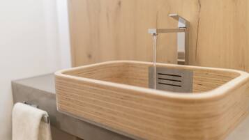 A modern bathroom with a wooden sink, a towel rack, and a wooden wall.