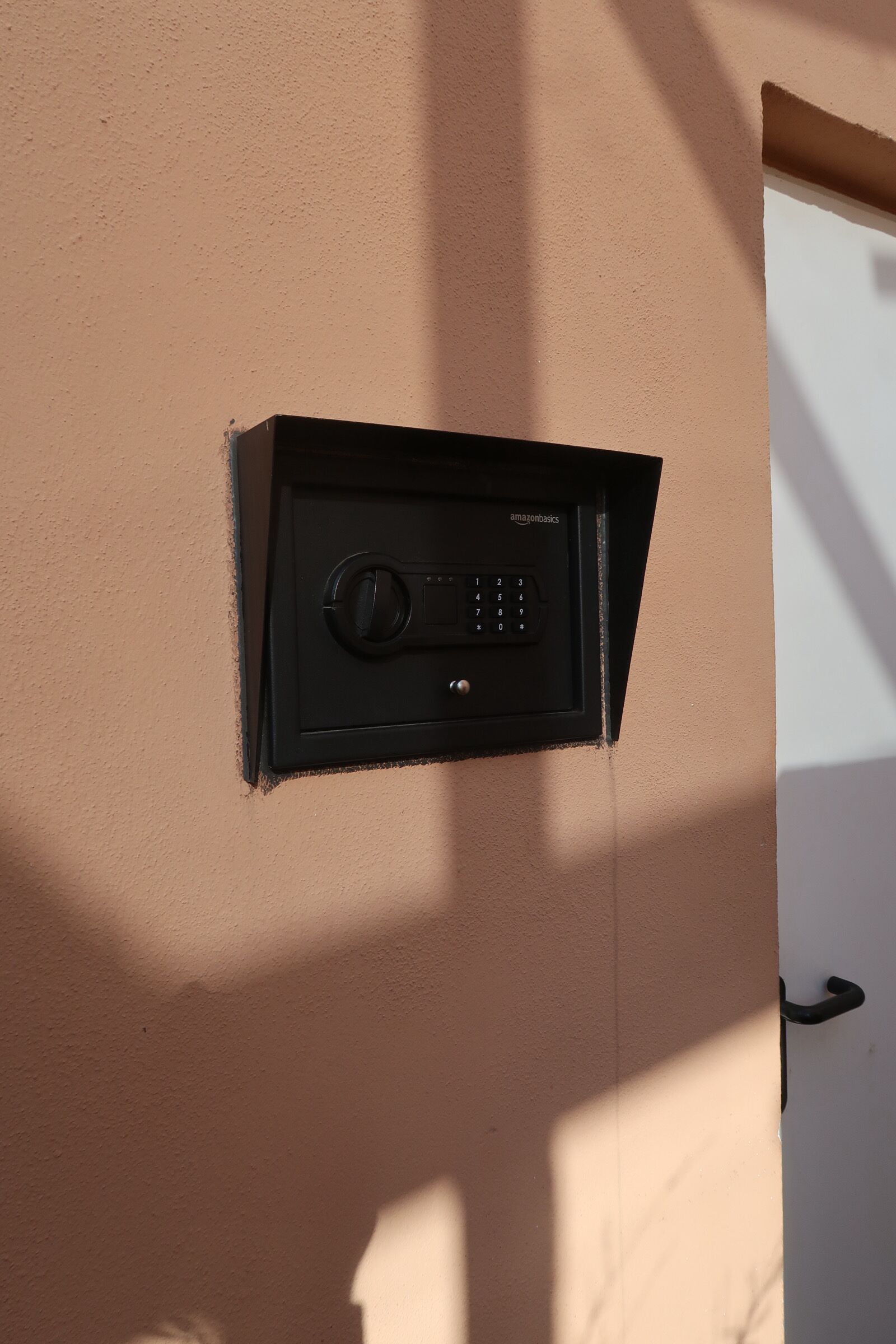 Um interfone preto AmazonBasics fixado numa parede cor de pêssego.