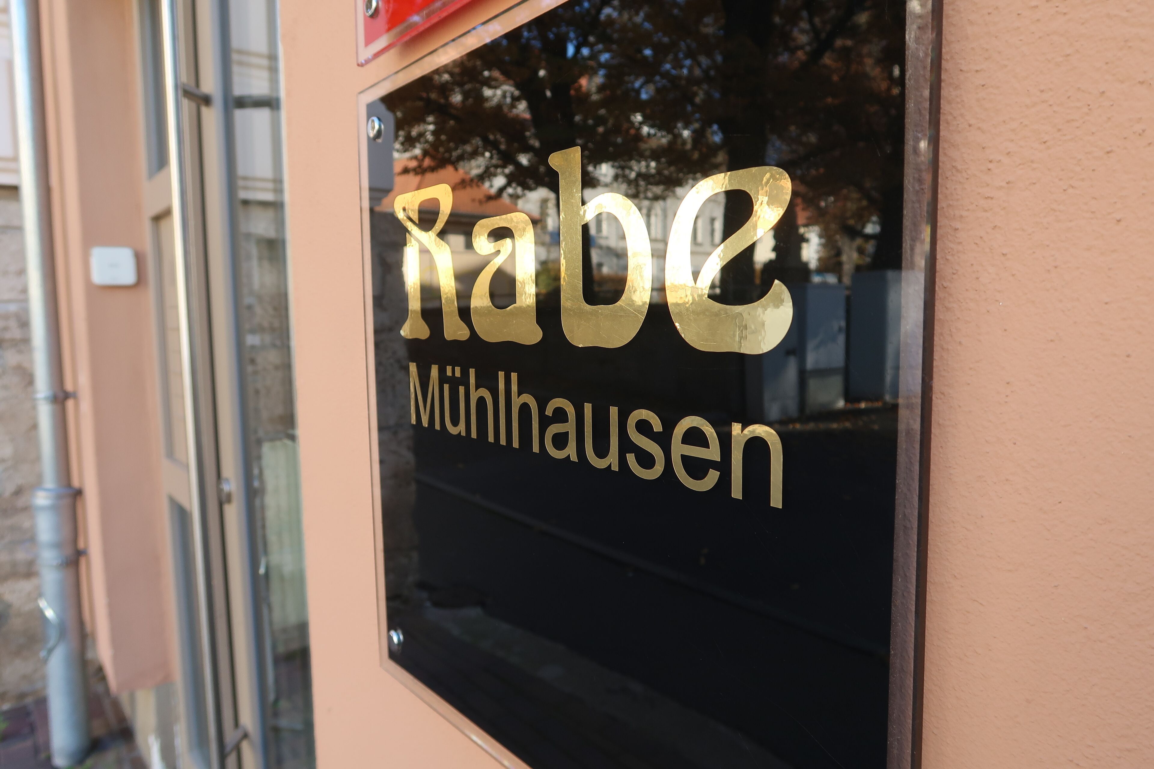 Une enseigne portant le nom « Rabe Mühlausen », en lettres dorées sur un fond noir.