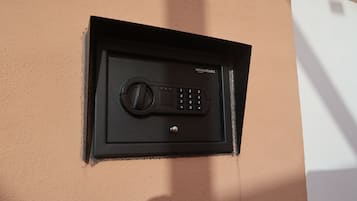 A black security keypad mounted on a peach-colored wall.