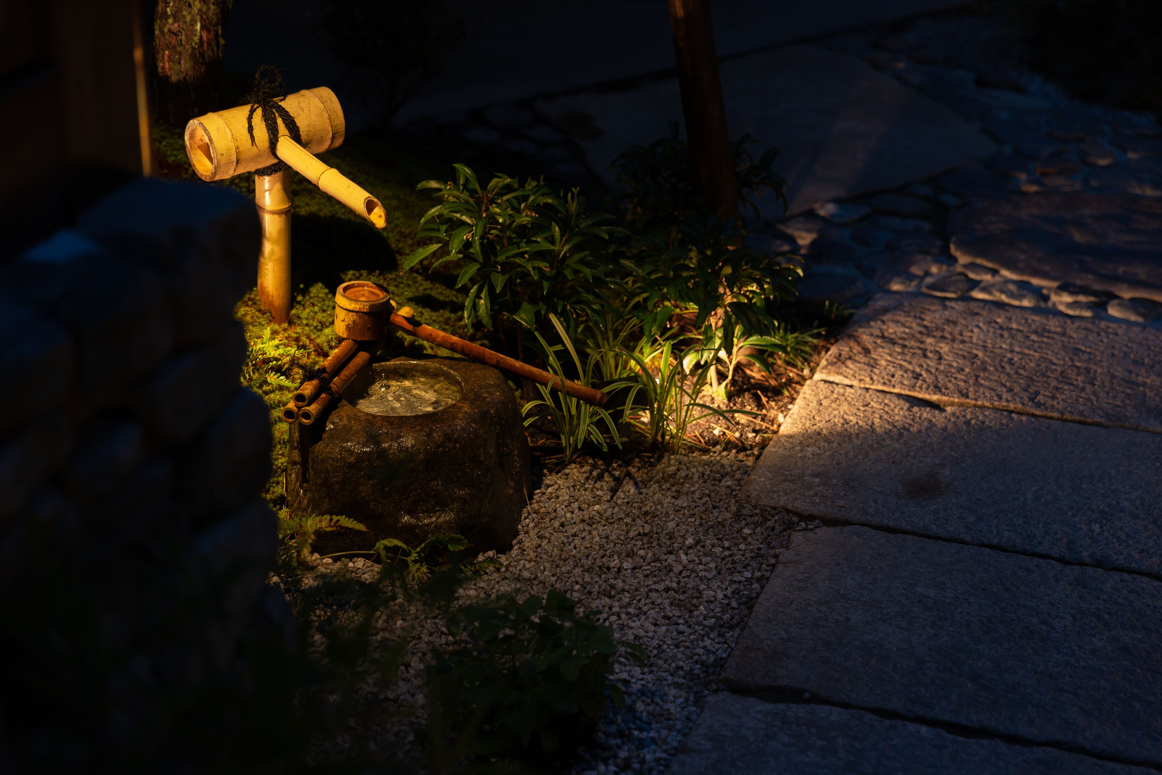 A rustic outdoor setting with a wooden hammer, a stone base, and a small plant.