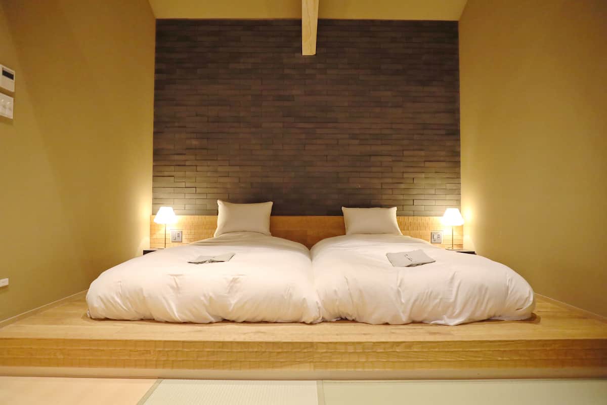 A double bed with two bedside tables, a brick-patterned headboard, and wall-mounted lamps.