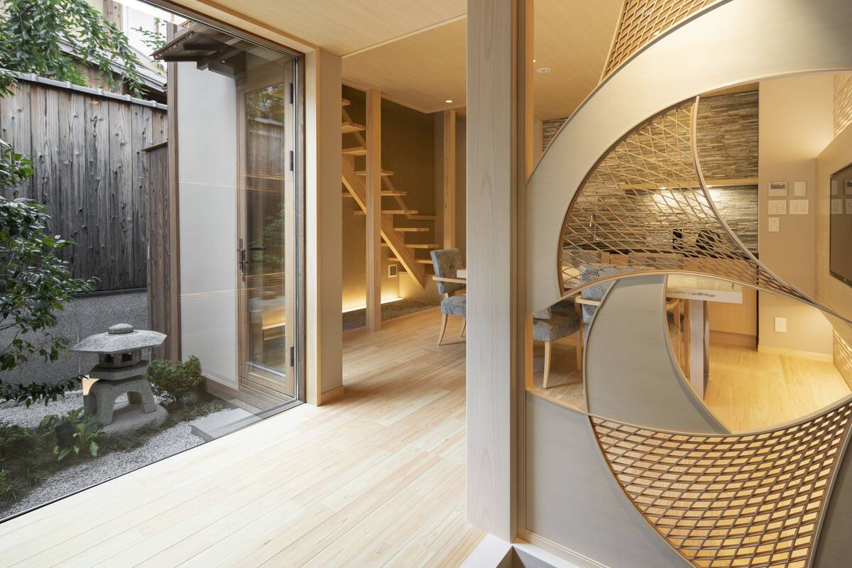 A modern interior with a wooden floor, a staircase, and a glass door leading outside.