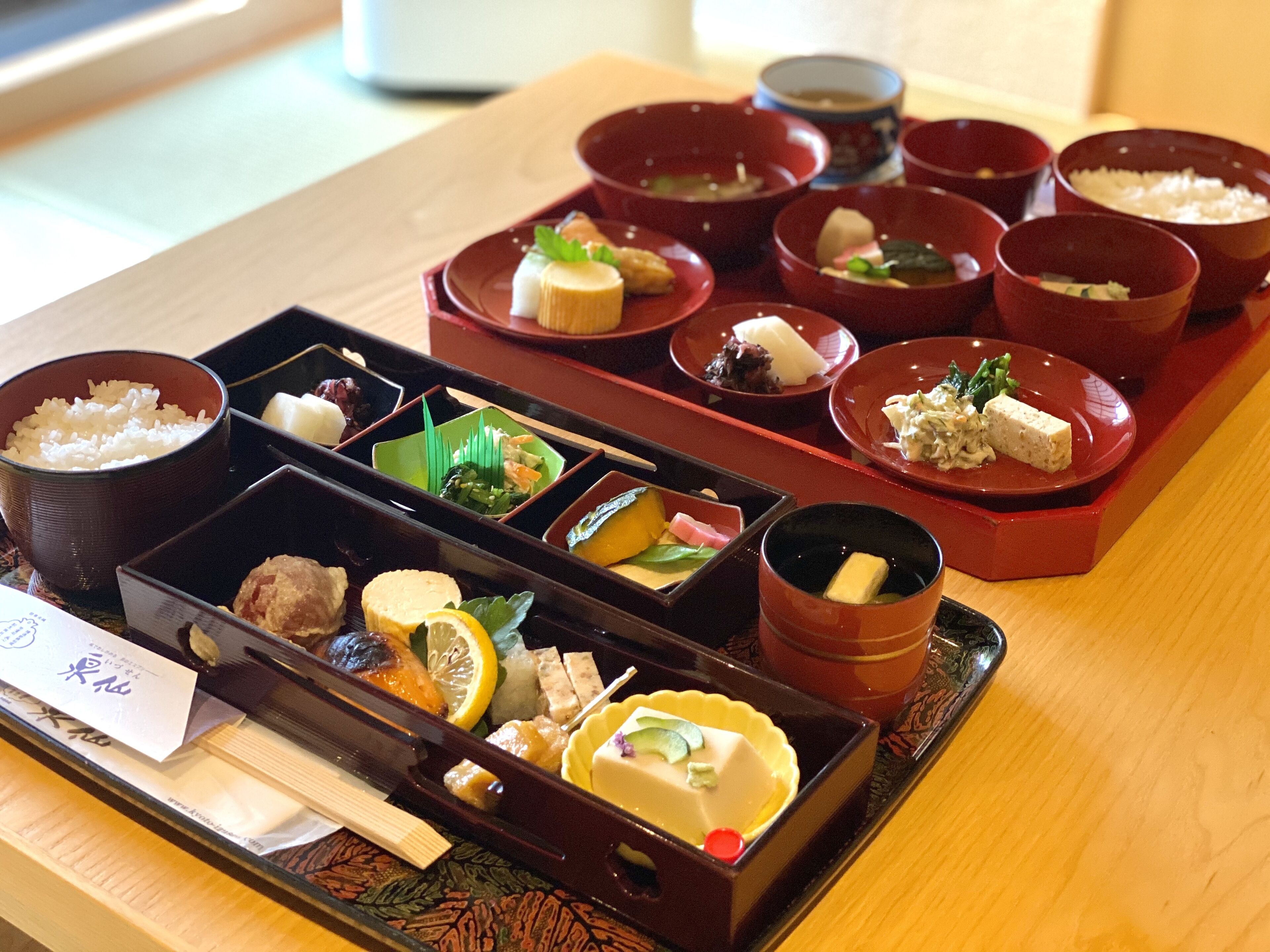 A traditional Japanese meal setup with various dishes in red and black bowls, arranged on a tray.