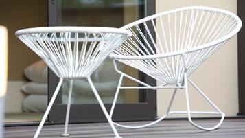 Dos sillas con estructura de alambre blanco sobre una terraza de madera.