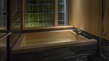 A modern bathroom with a large bathtub, a glass enclosure, and a shower area.