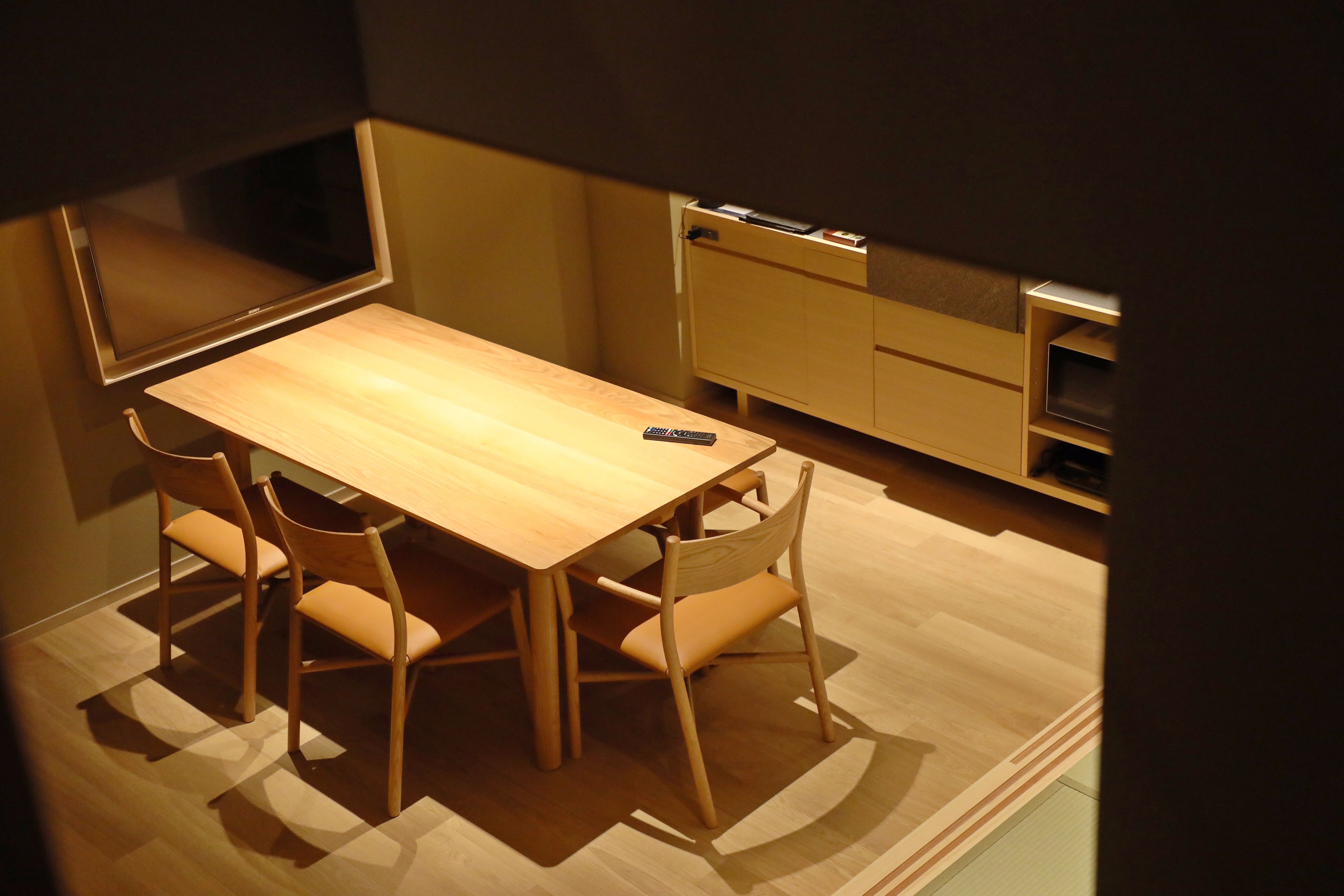 Un comedor pequeño con mesa y sillas de madera, un televisor y una pequeña cocina.