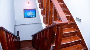 A wooden staircase with a handrail, a framed picture on the wall, and a light fixture. - Sea View Tourist Inn (Tangalle)