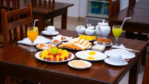 A breakfast table with plates of food, a glass of orange juice, and a pitcher of green juice. - Sea View Tourist Inn (Tangalle)