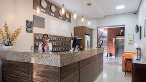 Een hotel receptie met een receptiebalie, klokken en een bordje sauna.