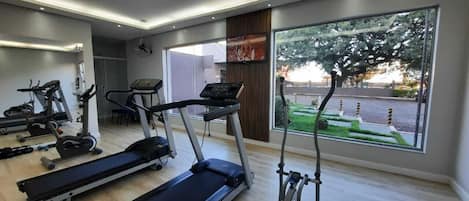 A modern gym with treadmills, elliptical machines, and a rowing machine.