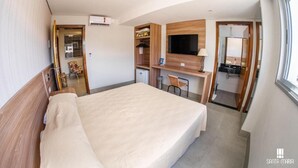 Een hotelkamer met een bed, bureau, televisie en een badkamer zichtbaar door een open deur.