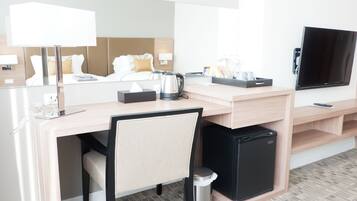 A hotel room with a desk, chair, television, and a bed with a headboard.