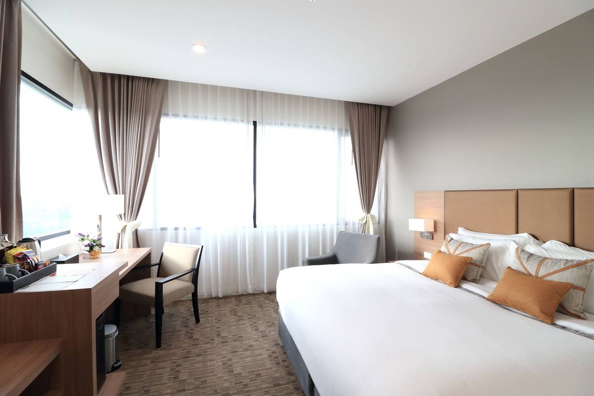 Quarto de hotel com uma cama grande, uma escrivaninha e uma cadeira.