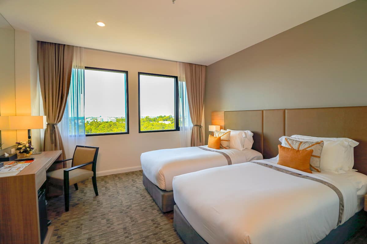 Quarto de hotel com duas camas, uma escrivaninha e uma cadeira.