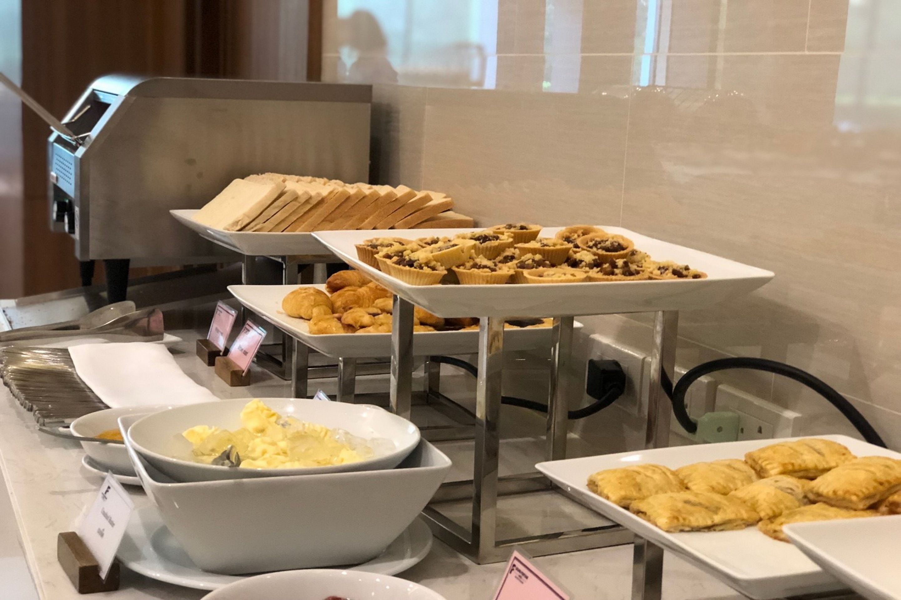 A buffet with various food items including pastries, bread, and a bowl of scrambled eggs.