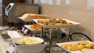 A buffet with various food items including pastries, bread, and a bowl of scrambled eggs.