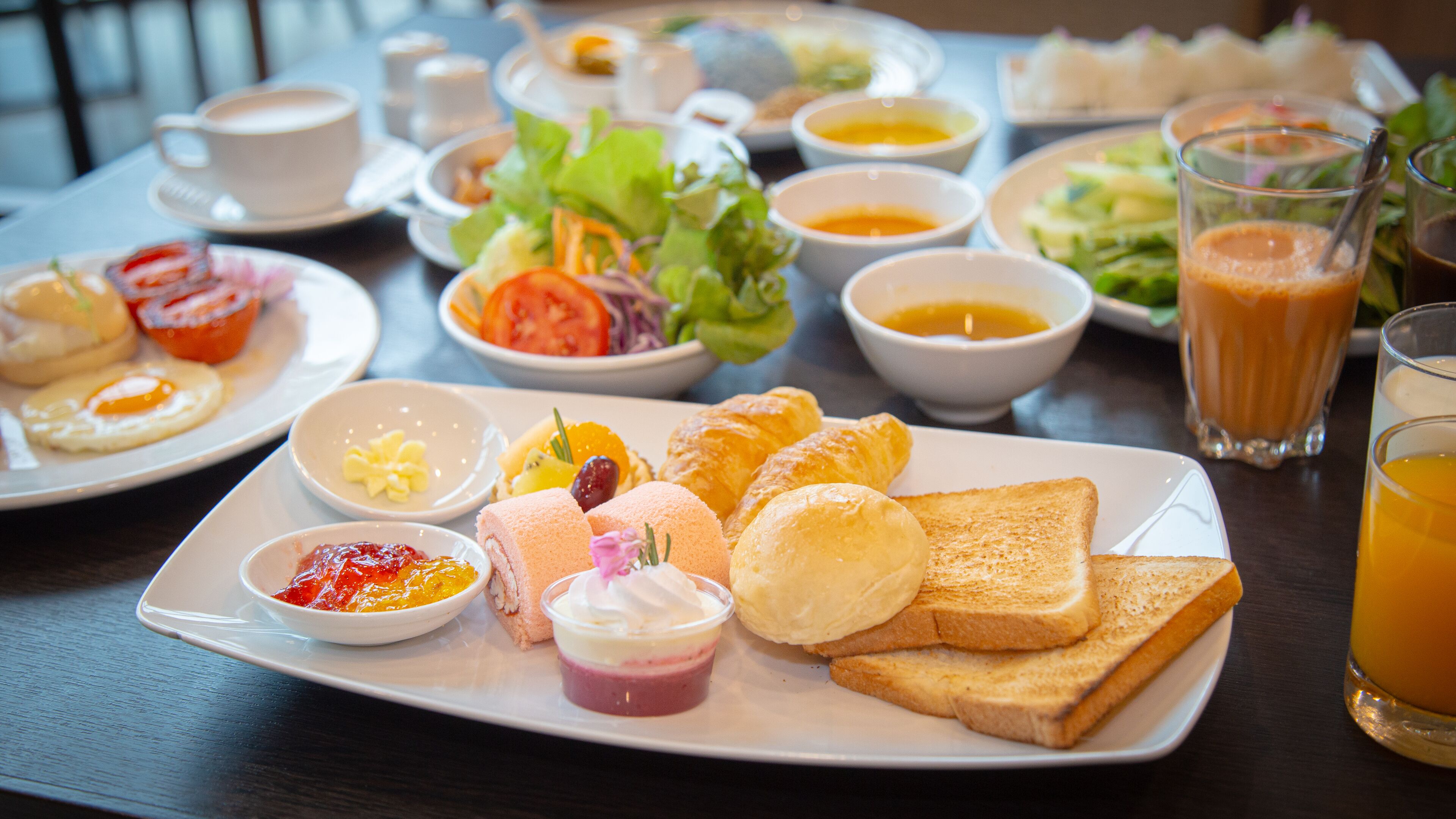 Un buffet de petit-déjeuner proposant divers plats, notamment des toasts, des viennoiseries et une salade.