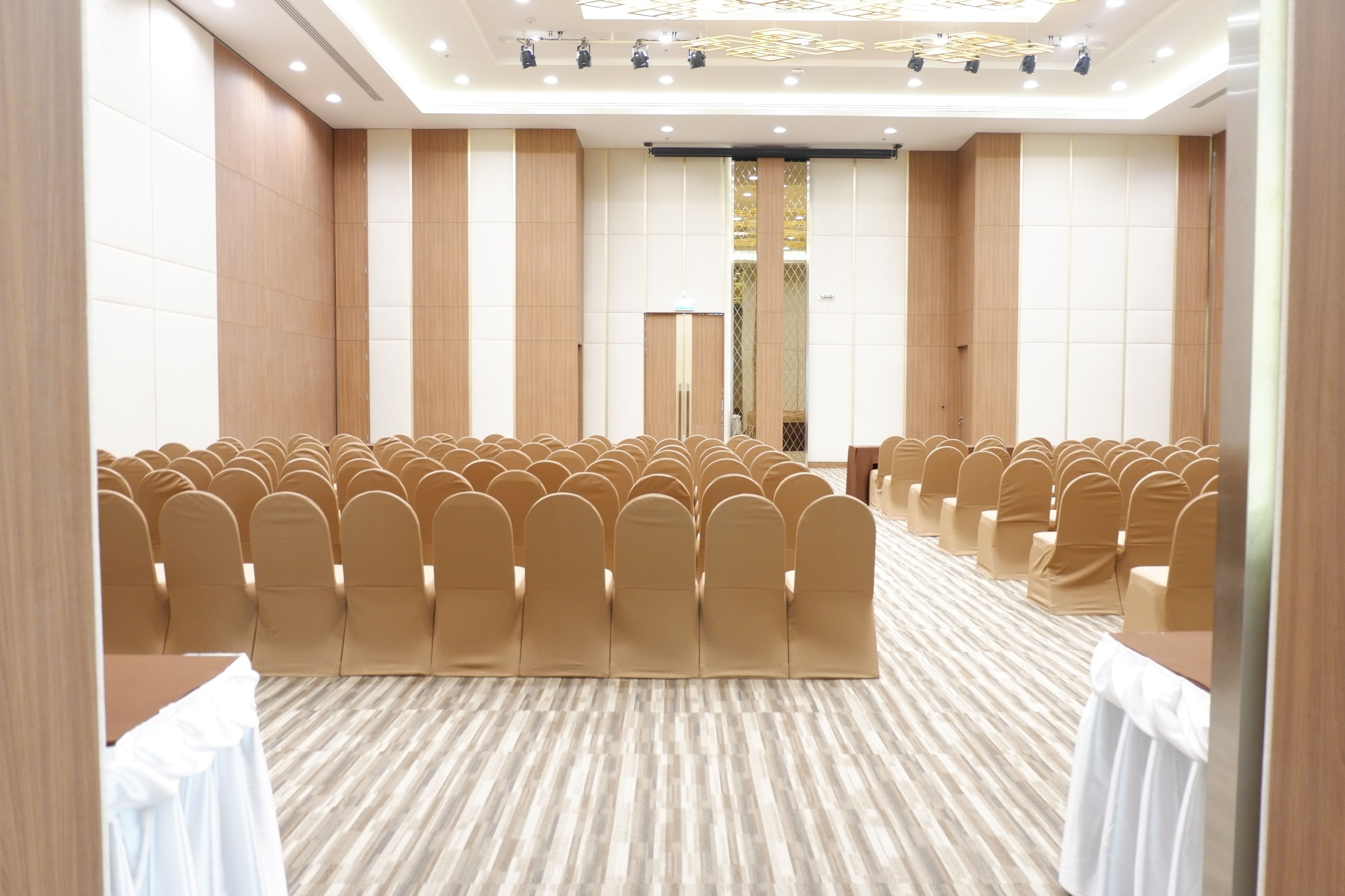 Un salón de conferencias con hileras de sillas y piso alfombrado.