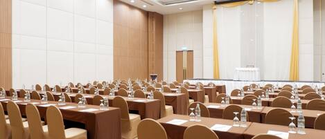 Un salón de conferencias con filas de mesas y sillas, equipado con botellas de agua y tarjetas de identificación.