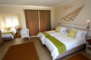 Ein Hotelzimmer mit zwei Betten, einem Sessel, einem Nachttisch und einer Wand mit dekorativer Gestaltung.