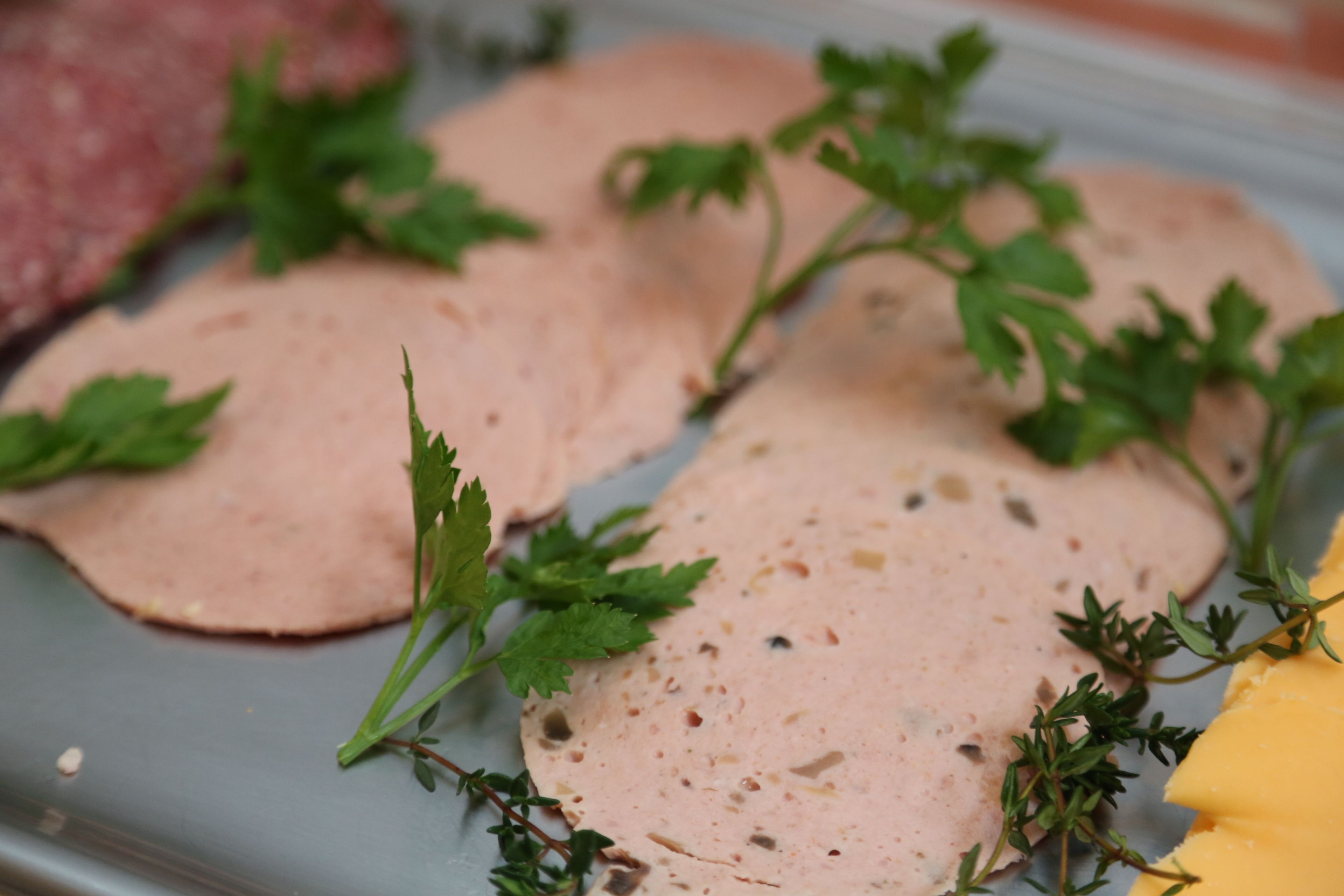 A tray with sliced meat and herbs.