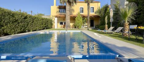 A swimming pool with lounge chairs and a building in the background.