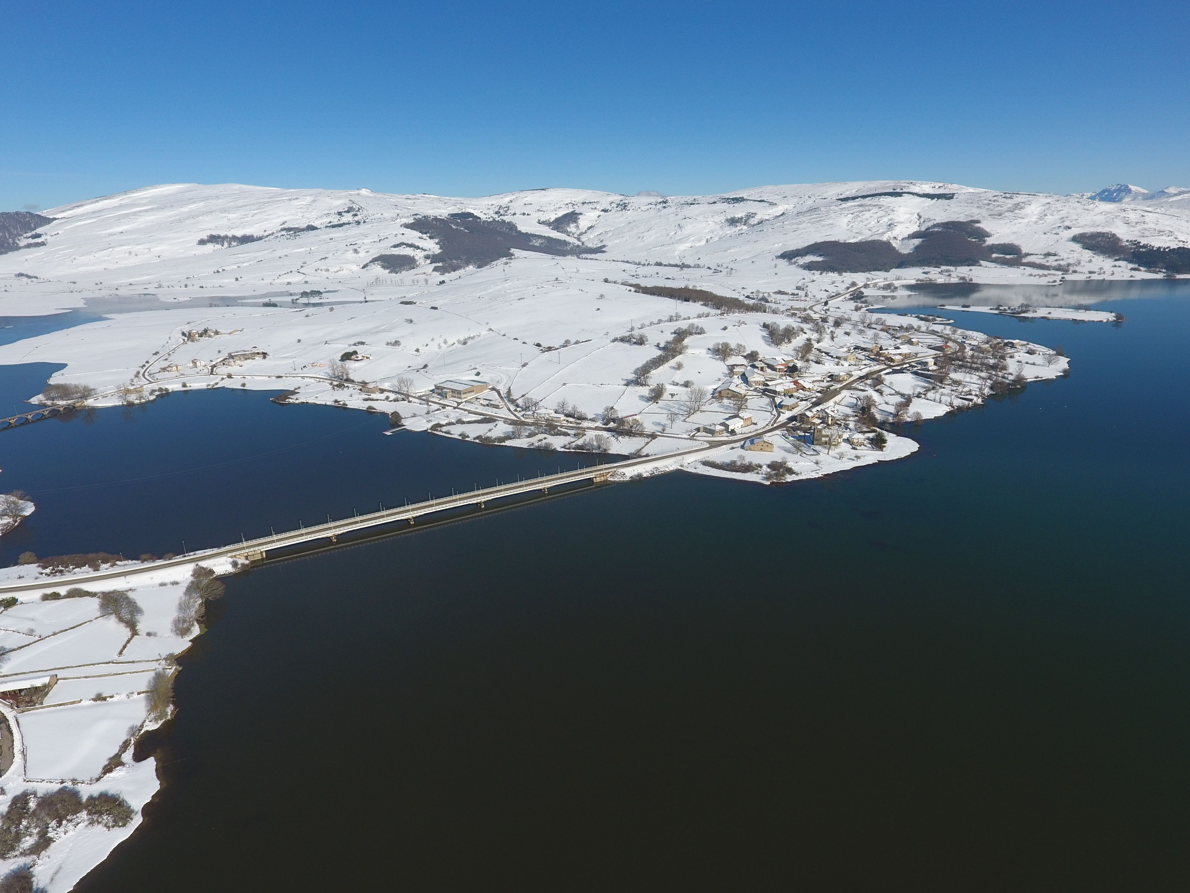An aerial view of a snow-covered island with a bridge connecting it to the mainland.