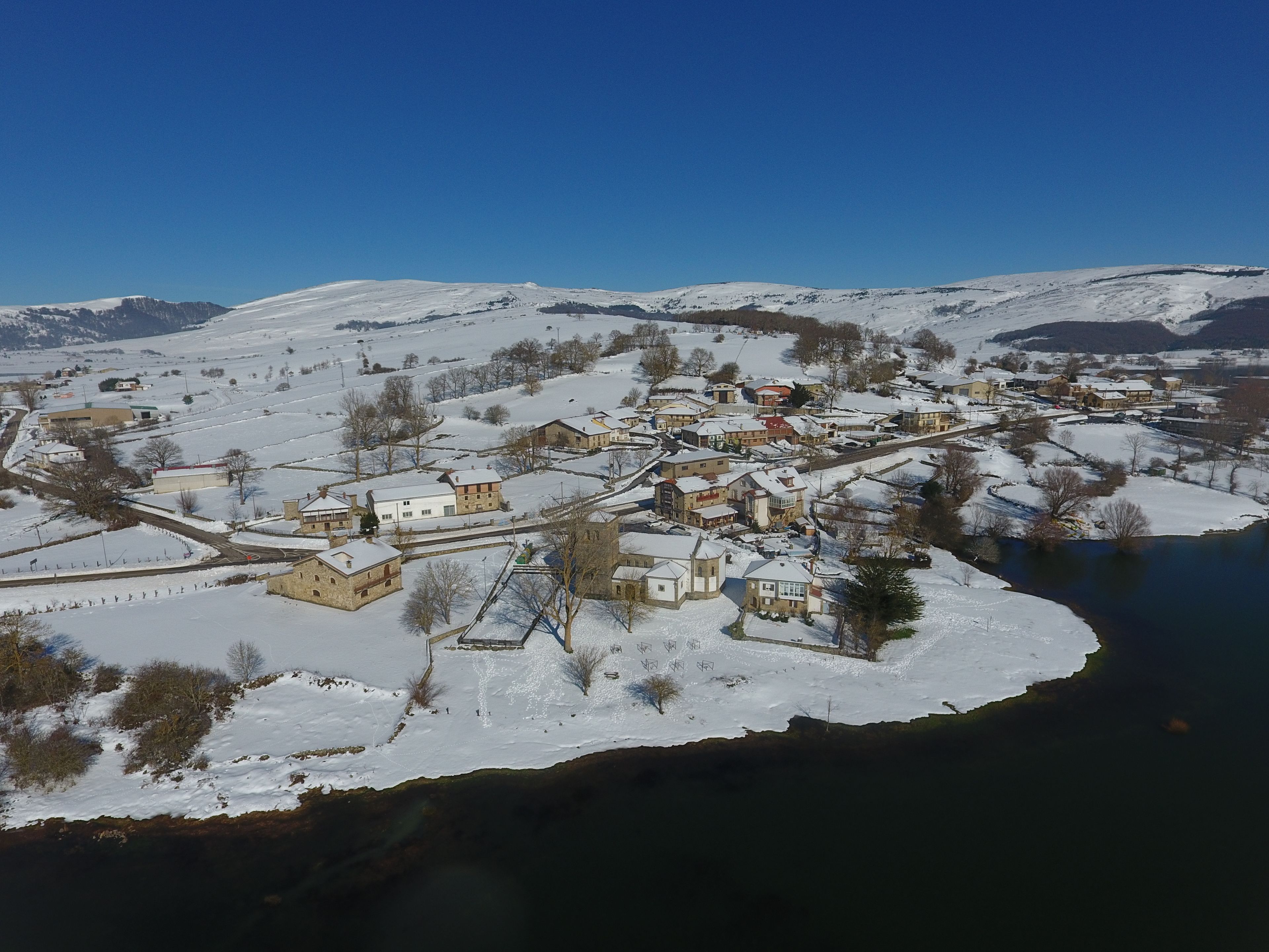 A snow-covered village with buildings clustered around a river.